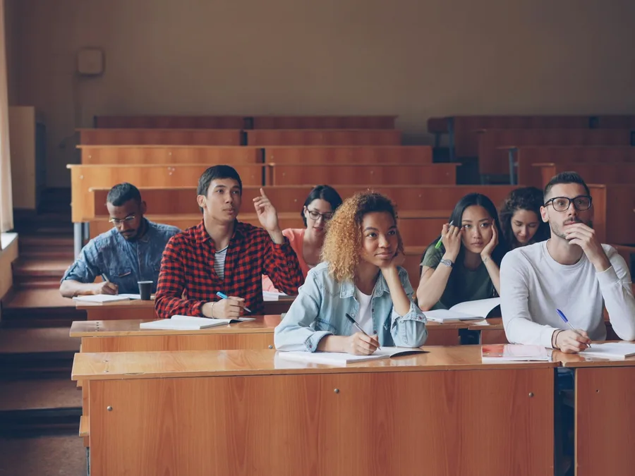 Students raising their hands in a lecture hall
